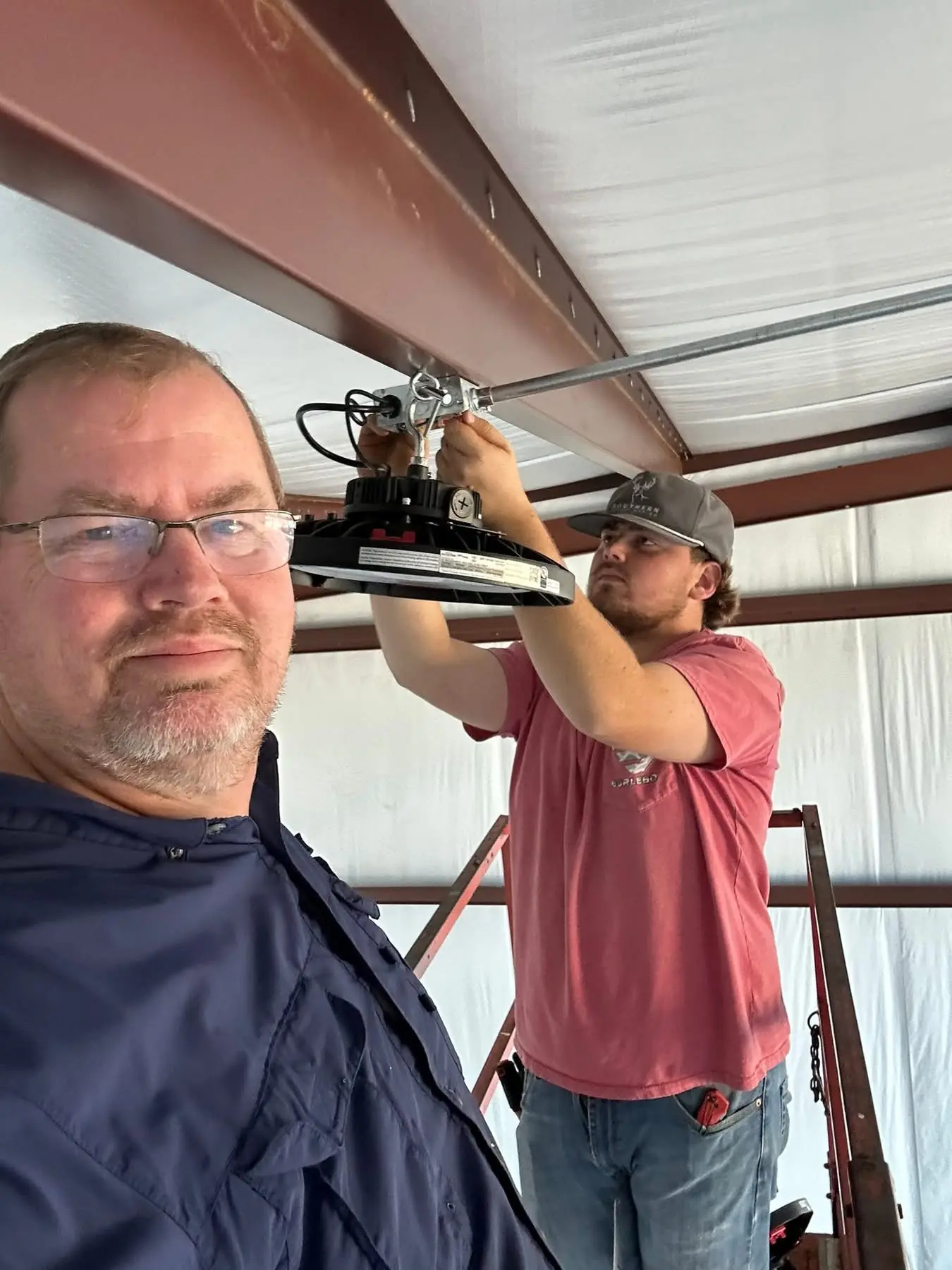 Whitehouse Electric electricians installing a commercial high-bay LED light fixture in Southeast Georgia.